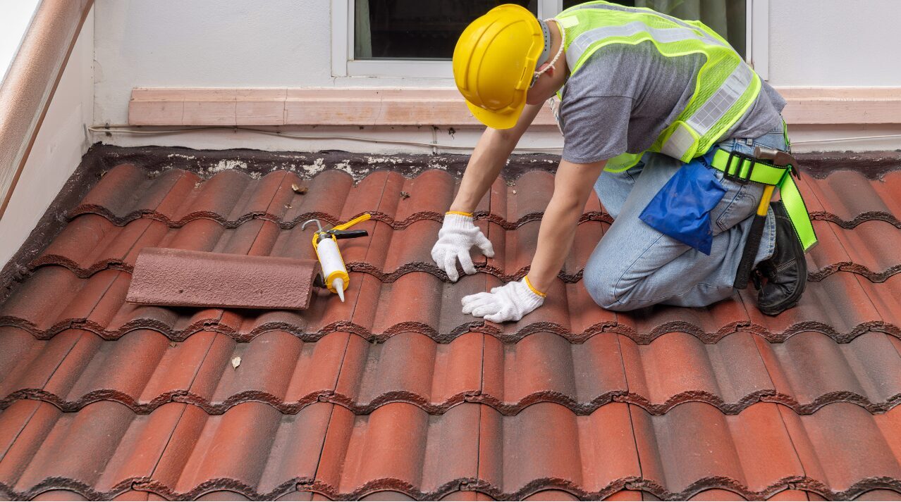 Worker replacing damaged roof tile