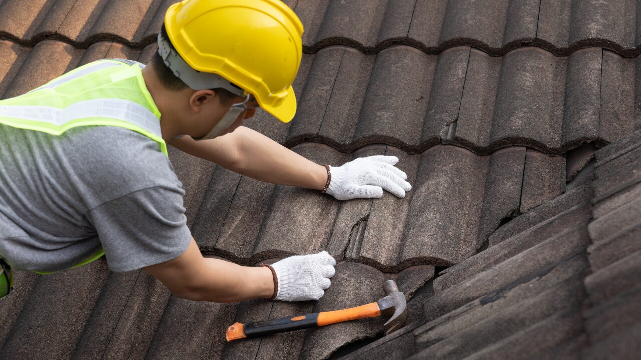 Worker replacing damaged roof tile
