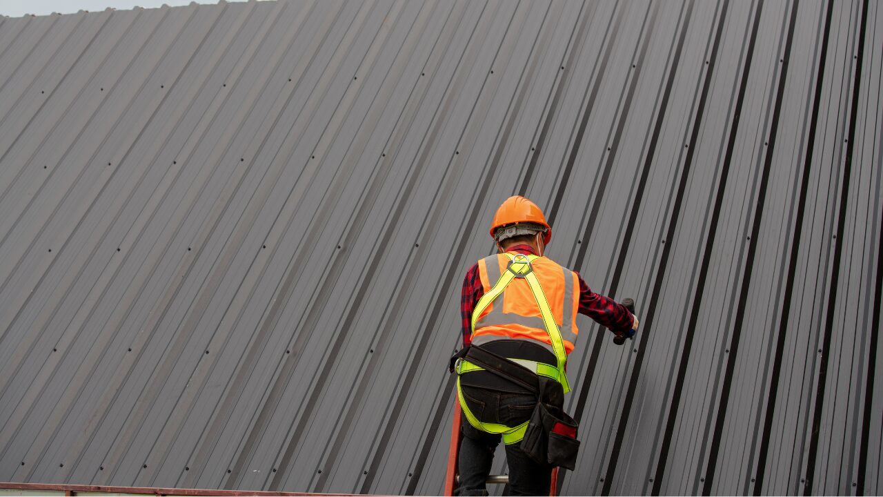 Roofer securing metal roofing panels